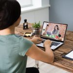 Young Woman Videoconferencing With Colleague On Computer At Desk