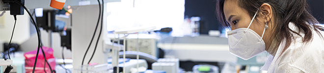 Lab researcher looking through microscope.