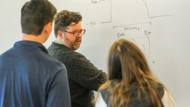 Patrick Boyle and two members of his team working data on a blackboard.