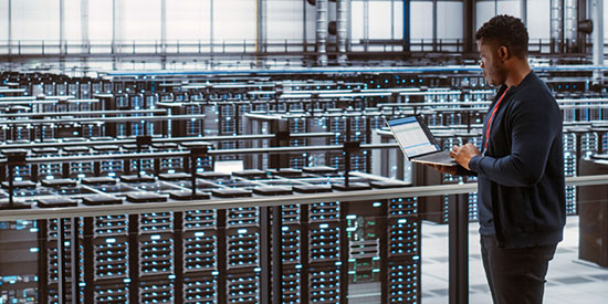 a man on a laptop in a server room