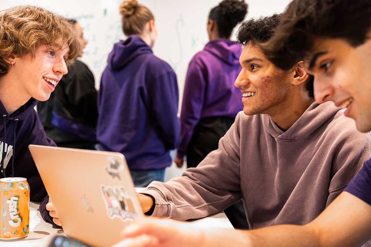 Three smiling UW students with laptop.